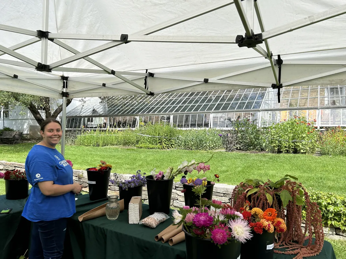 People choosing stems from a flower table under a white tent