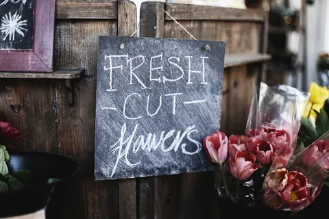 Buckets of fresh cut roses beside a chalkboard sign