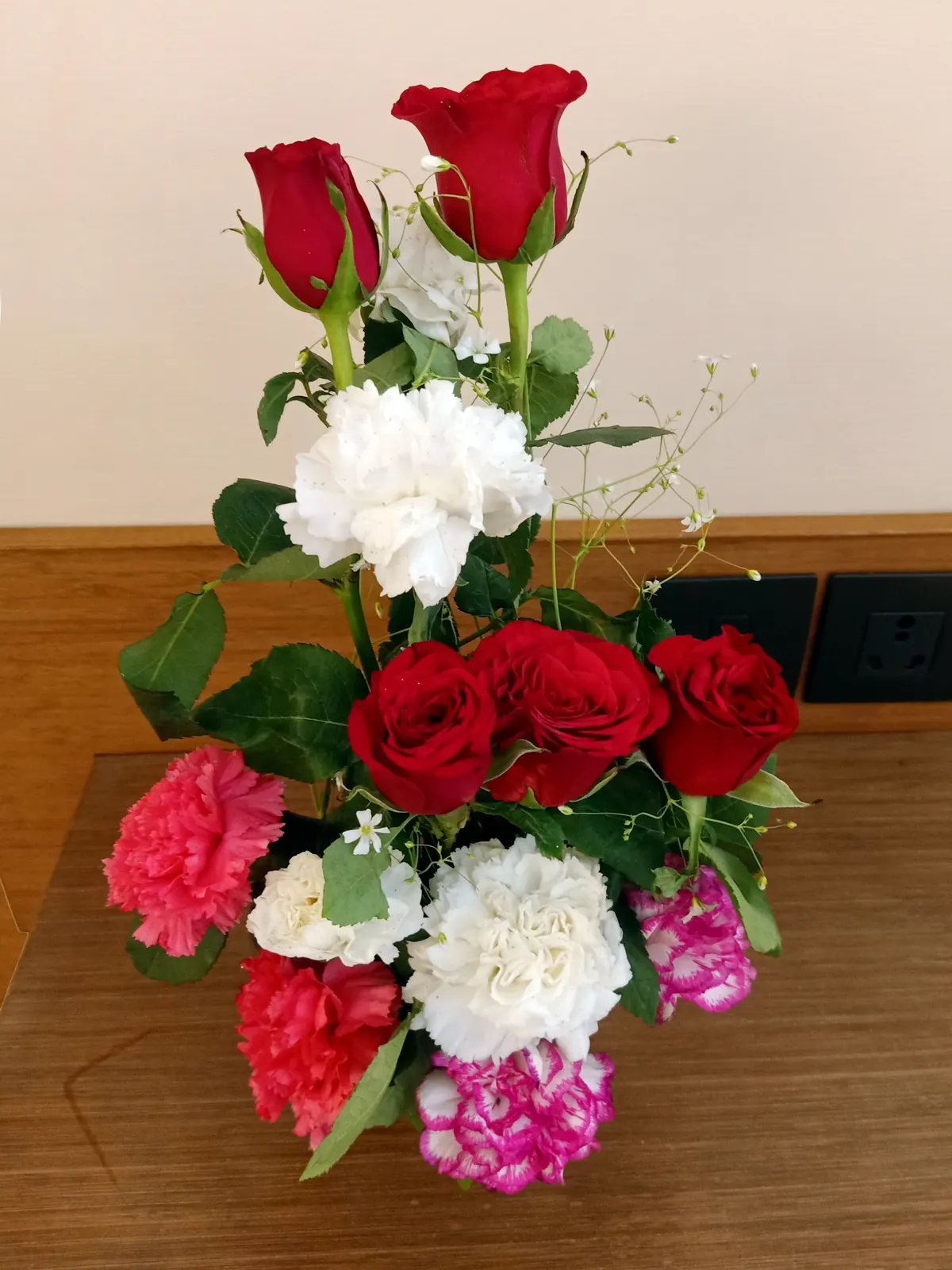 A bouquet of red roses and white carnations wrapped in paper