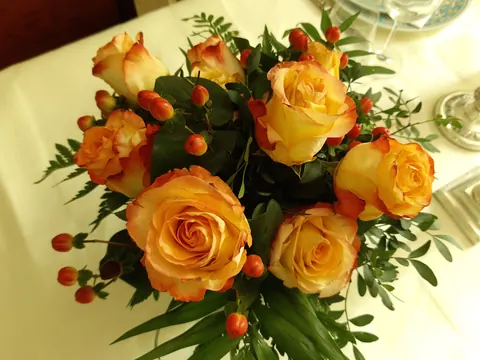 Orange roses with small berries in a table arrangement